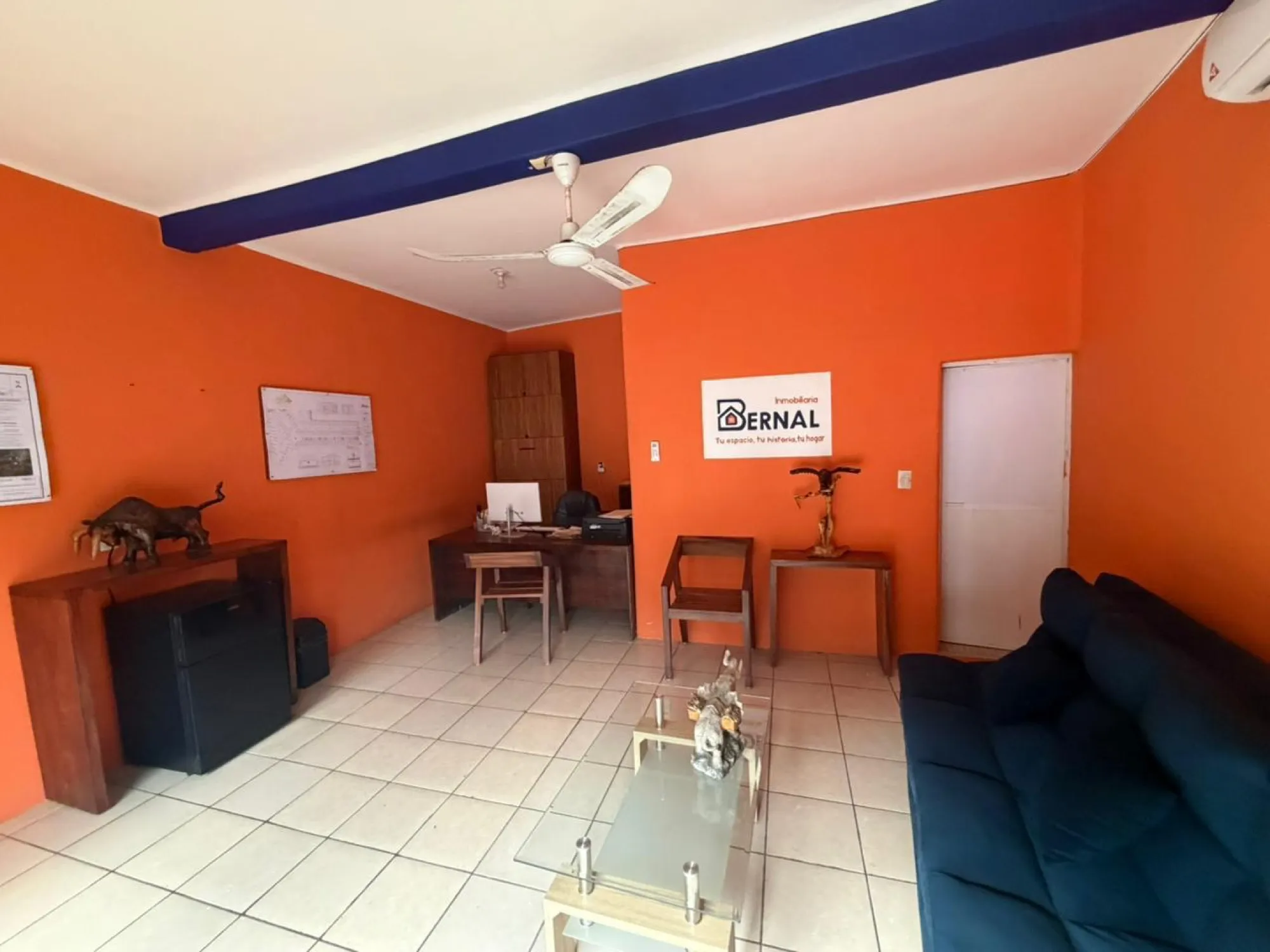 Interior de una oficina con paredes naranjas, una viga azul y un sillón
