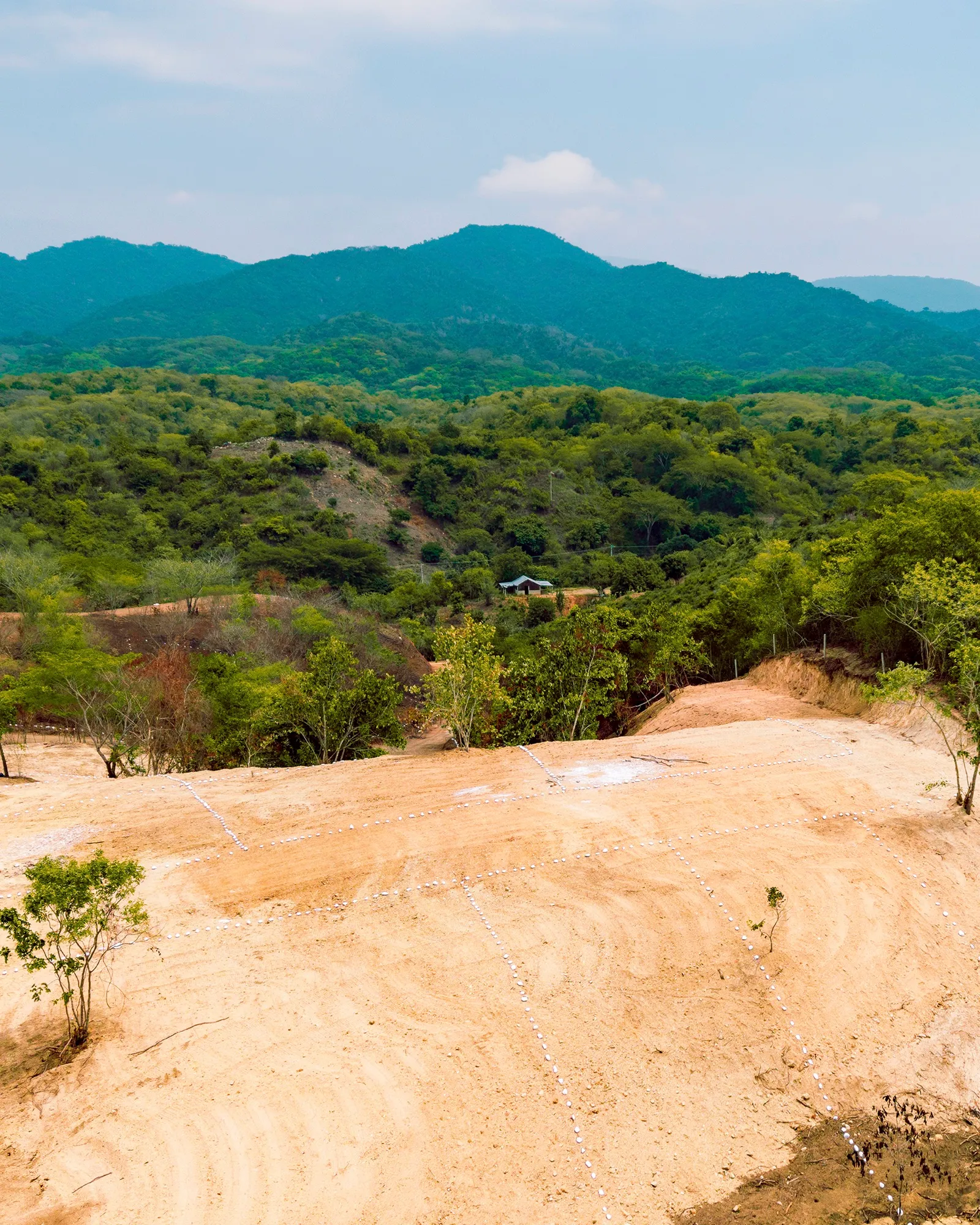 Terreno de tierra con cerros y cielo al fondo